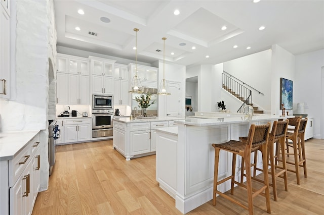 13414 Shore Vista Dr, Austin, TX 78732 - kitchen featuring a large island with sink, coffered ceiling, stainless steel appliances, light wood-style floors, and white cabinets
