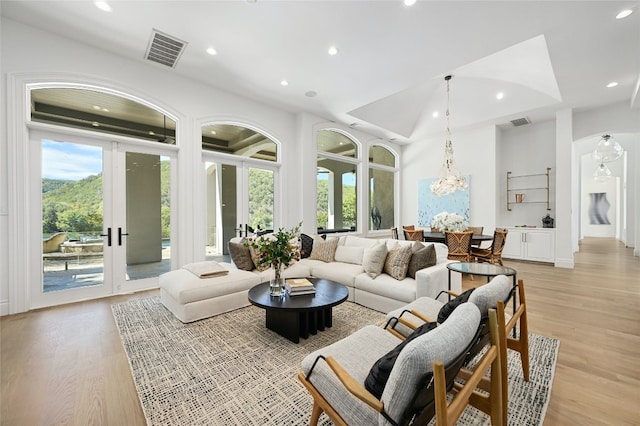 living room with french doors, light hardwood / wood-style floors, and a notable chandelier