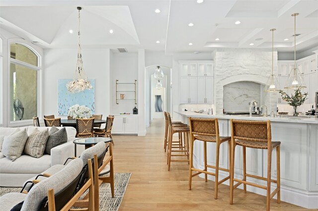 kitchen featuring backsplash, a kitchen breakfast bar, white cabinetry, and light wood-type flooring