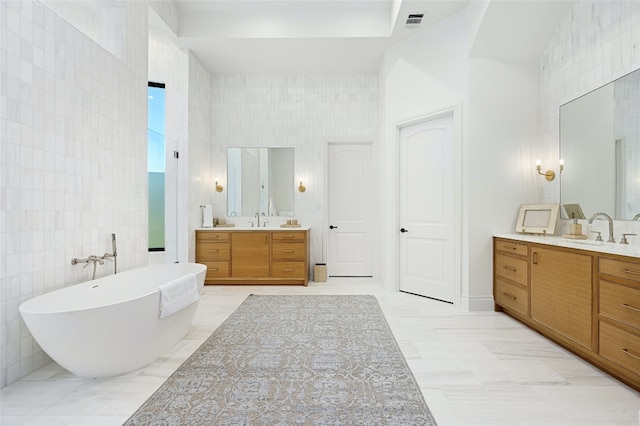 bathroom with a bathing tub, vanity, and tile walls