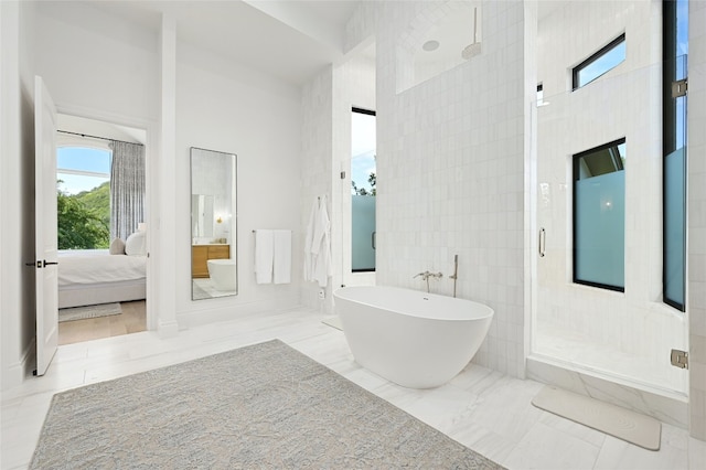 ensuite bathroom with a freestanding tub, marble finish floor, a stall shower, ensuite bath, and tile walls