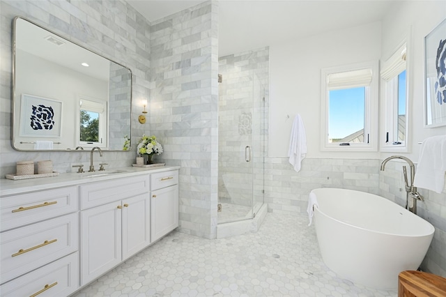 bathroom with separate shower and tub, tile patterned flooring, vanity, and tile walls