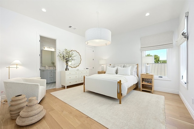 bedroom featuring light wood-type flooring and connected bathroom