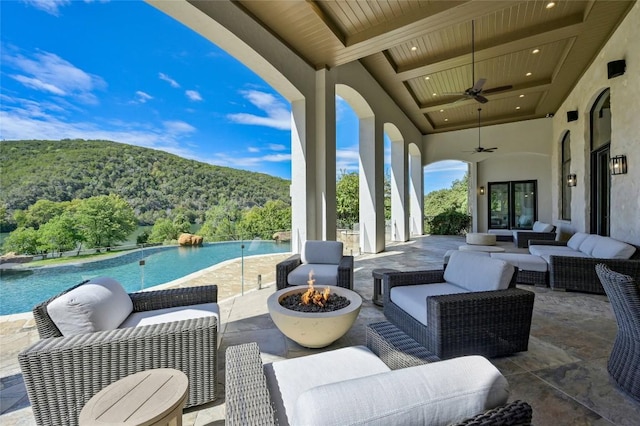 view of patio / terrace with ceiling fan, a mountain view, and an outdoor living space with a fire pit