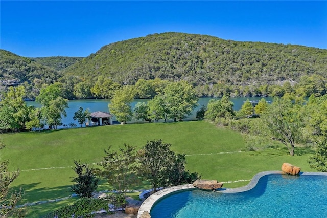 view of swimming pool featuring a yard and a water and mountain view