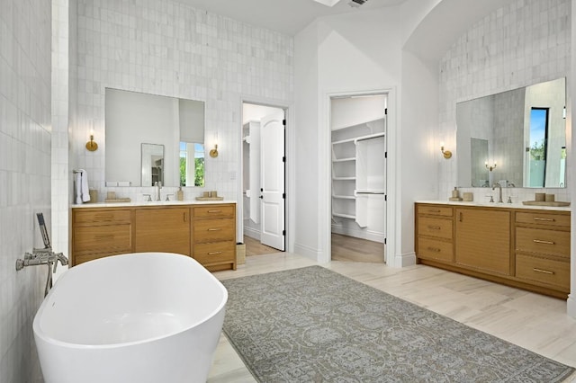 13414 Shore Vista Dr, Austin, TX 78732 - bathroom featuring two vanities, a soaking tub, tasteful backsplash, a walk in closet, and a high ceiling