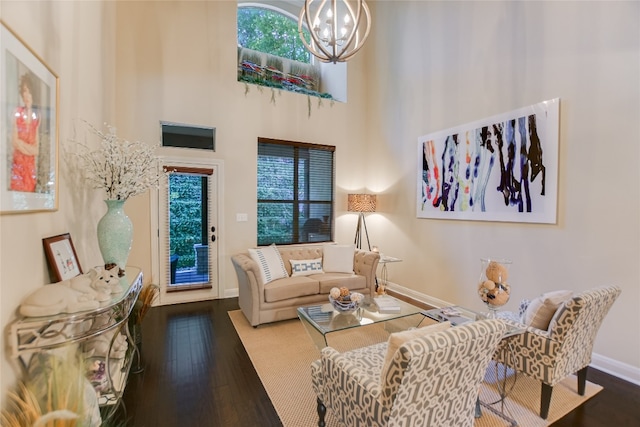 living room featuring dark hardwood / wood-style floors, a towering ceiling, and a notable chandelier