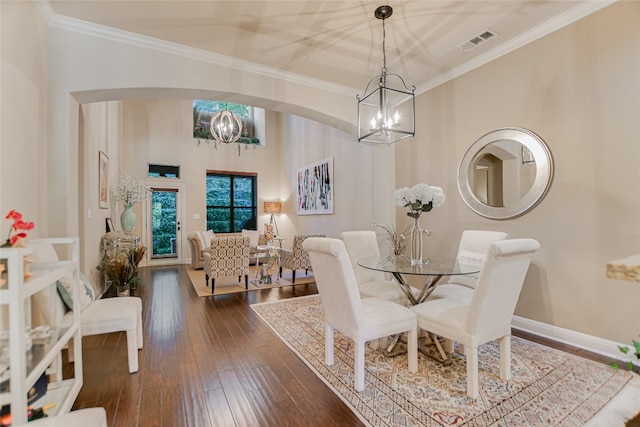 dining area with dark wood-type flooring, ornamental molding, and a chandelier