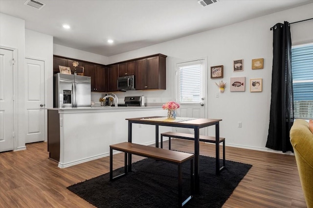 kitchen with wood-type flooring, appliances with stainless steel finishes, sink, and dark brown cabinetry