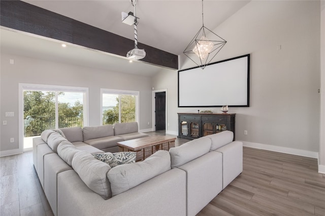 home theater room featuring lofted ceiling, wood-type flooring, and an inviting chandelier