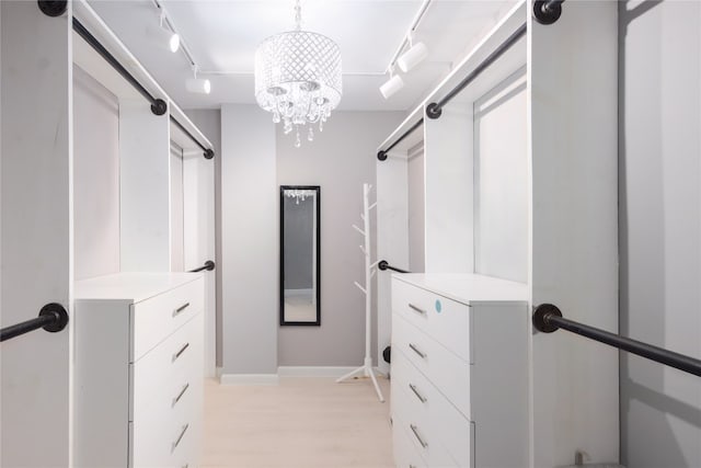 spacious closet featuring an inviting chandelier and light hardwood / wood-style floors