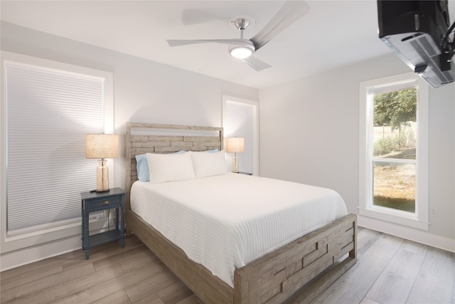 bedroom featuring light wood-type flooring, multiple windows, and ceiling fan