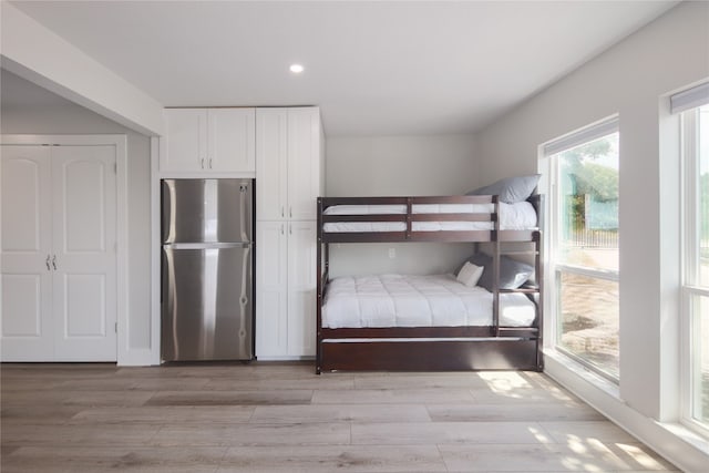 unfurnished bedroom with stainless steel fridge and light hardwood / wood-style flooring