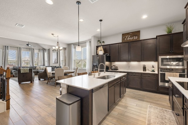 kitchen with ceiling fan with notable chandelier, a center island with sink, stainless steel appliances, and a healthy amount of sunlight