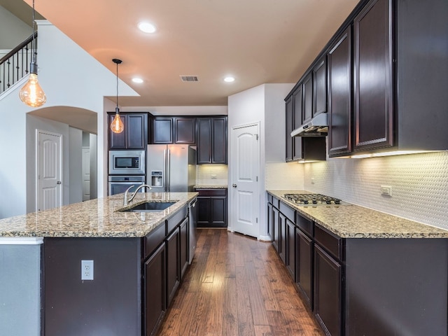 kitchen featuring pendant lighting, tasteful backsplash, dark wood-type flooring, stainless steel appliances, and sink