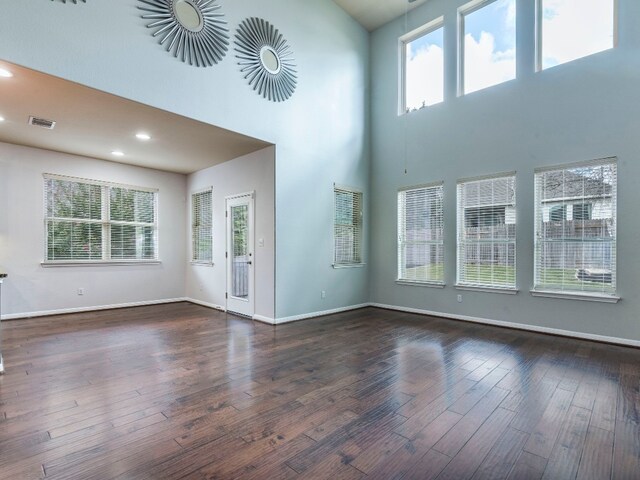 unfurnished living room featuring a high ceiling and dark hardwood / wood-style flooring