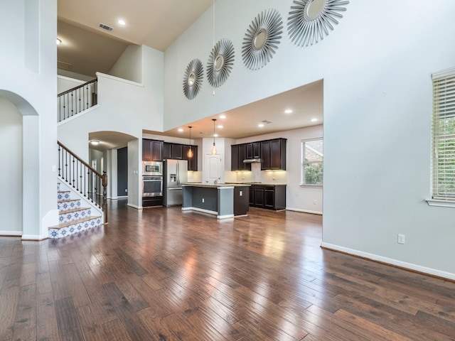 living room with dark hardwood / wood-style floors and a towering ceiling