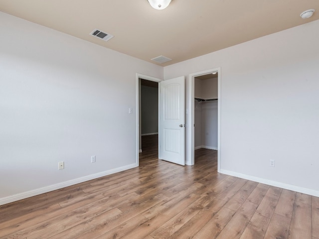 unfurnished bedroom featuring a closet, wood-type flooring, and a spacious closet