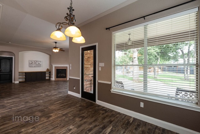 unfurnished room with a tiled fireplace, a wealth of natural light, and dark hardwood / wood-style floors