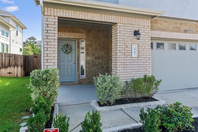 view of exterior entry with a lawn and a garage