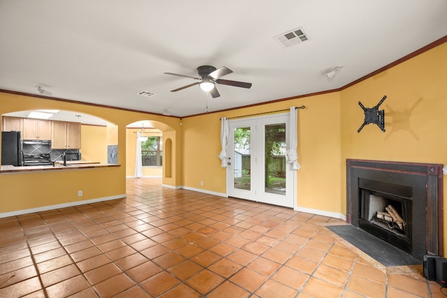 unfurnished living room with crown molding, light tile patterned floors, sink, ceiling fan, and french doors