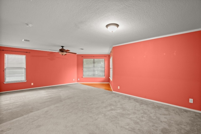 carpeted spare room featuring a textured ceiling, crown molding, and ceiling fan