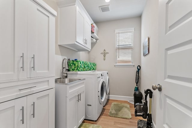 laundry area featuring washer and dryer, light hardwood / wood-style flooring, cabinets, and sink