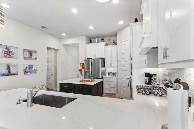 kitchen with white cabinetry, tasteful backsplash, stainless steel appliances, light stone counters, and sink