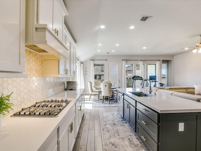 kitchen with light hardwood / wood-style floors, a kitchen island with sink, sink, ceiling fan, and white cabinets