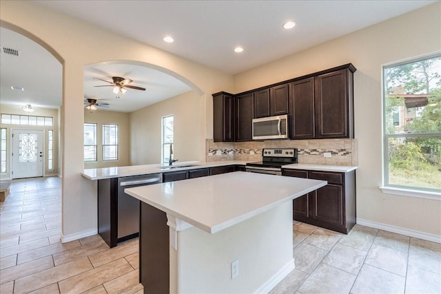 kitchen with a healthy amount of sunlight, stainless steel appliances, backsplash, and kitchen peninsula