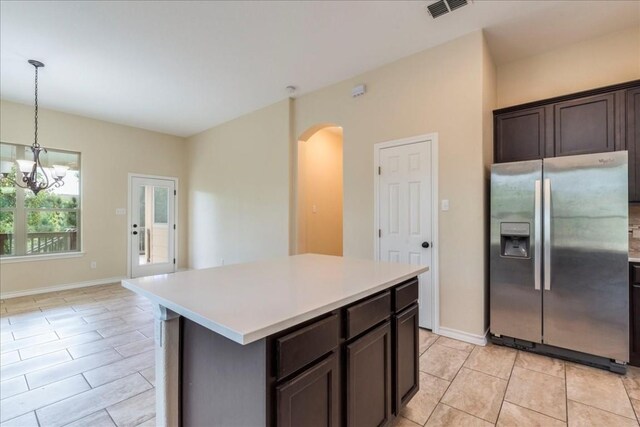 kitchen featuring a chandelier, hanging light fixtures, a center island, stainless steel fridge, and dark brown cabinetry