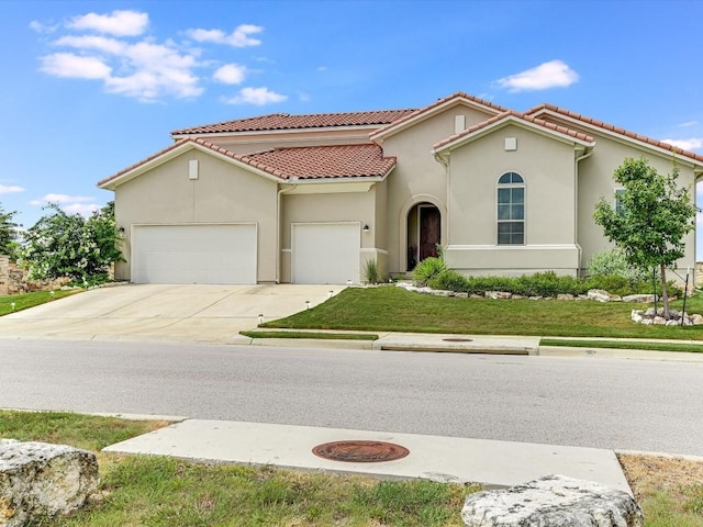 mediterranean / spanish-style house featuring driveway, an attached garage, a tile roof, and stucco siding