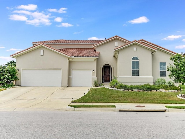 mediterranean / spanish-style house featuring a garage, a tiled roof, concrete driveway, stucco siding, and a front yard