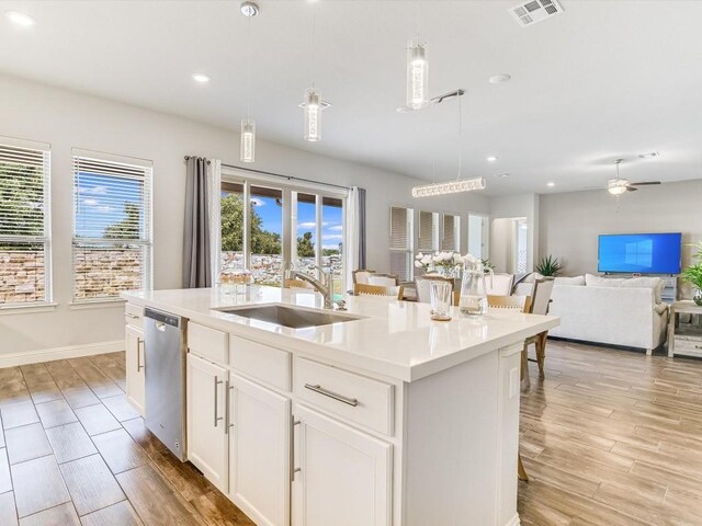 kitchen with a center island with sink, dishwasher, sink, and light hardwood / wood-style floors