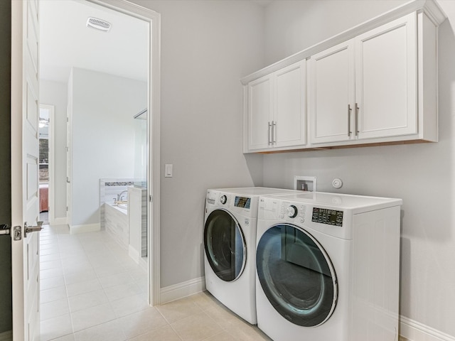 laundry area featuring cabinets, independent washer and dryer, and light tile patterned flooring