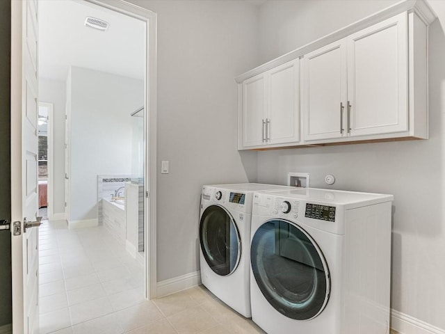 clothes washing area with light tile patterned flooring, visible vents, baseboards, independent washer and dryer, and cabinet space