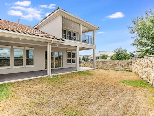 back of property with a patio, a balcony, a tiled roof, a yard, and stucco siding