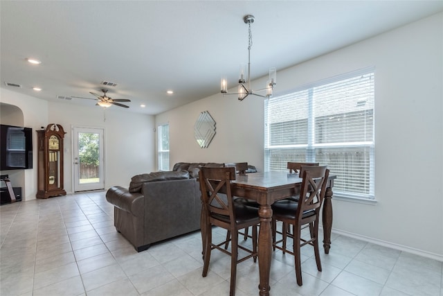 tiled dining room featuring ceiling fan with notable chandelier