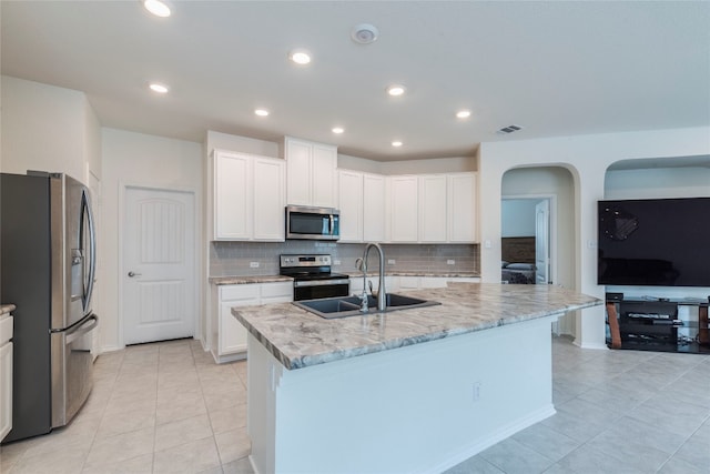 kitchen with white cabinetry, backsplash, an island with sink, sink, and appliances with stainless steel finishes