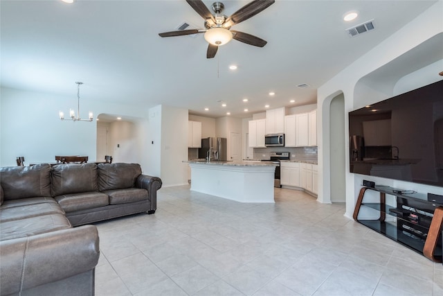 tiled living room featuring ceiling fan with notable chandelier