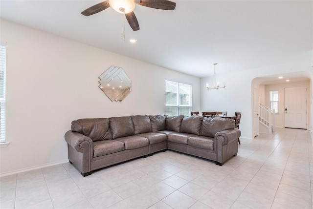 living room featuring ceiling fan with notable chandelier, a healthy amount of sunlight, and light tile patterned floors