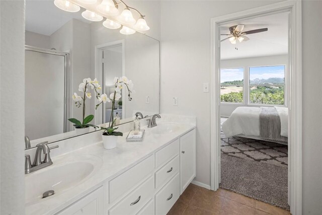 ensuite bathroom with tile patterned floors, a stall shower, double vanity, and a sink