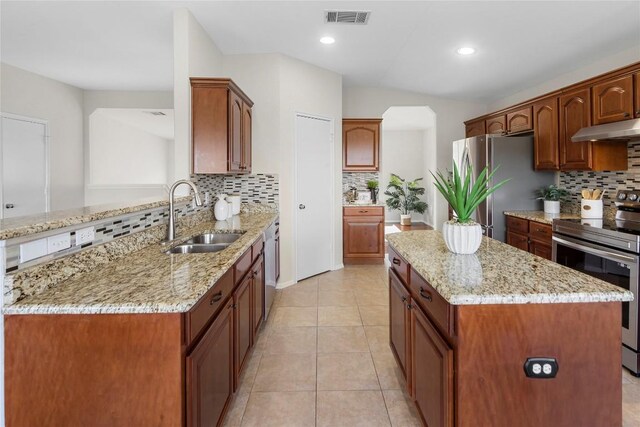 kitchen featuring visible vents, a kitchen island, under cabinet range hood, stainless steel appliances, and a sink