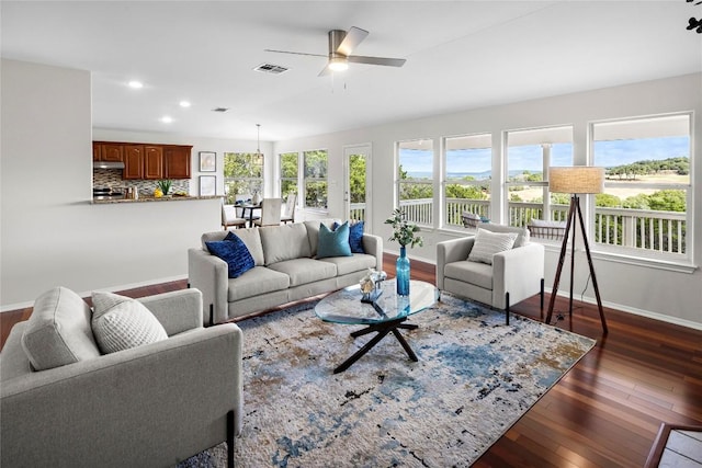 living room featuring visible vents, baseboards, recessed lighting, a ceiling fan, and dark wood-style flooring