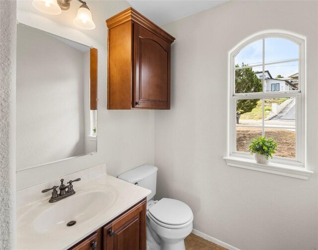 half bathroom with vanity, toilet, and baseboards