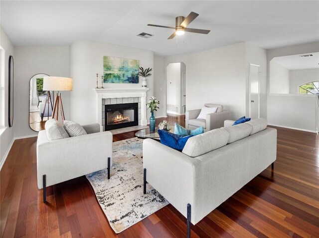 living room featuring visible vents, a ceiling fan, wood finished floors, and a tiled fireplace