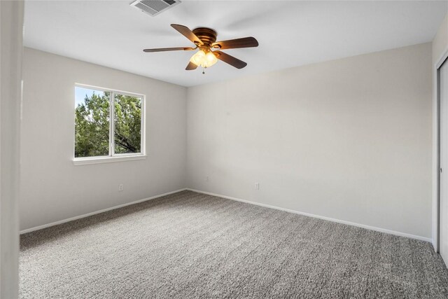 carpeted empty room with visible vents, baseboards, and a ceiling fan