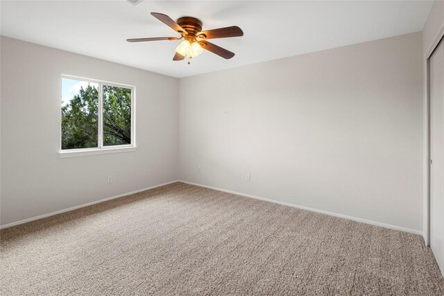 carpeted empty room with baseboards and a ceiling fan