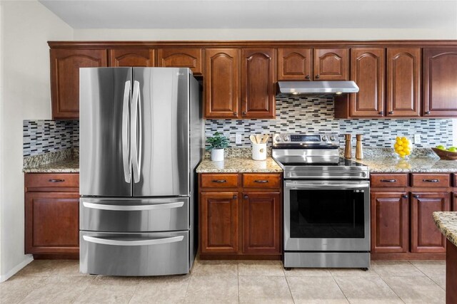 kitchen featuring under cabinet range hood, stainless steel appliances, light stone countertops, and tasteful backsplash