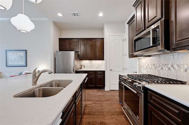 kitchen featuring tasteful backsplash, sink, dark wood-type flooring, hanging light fixtures, and appliances with stainless steel finishes